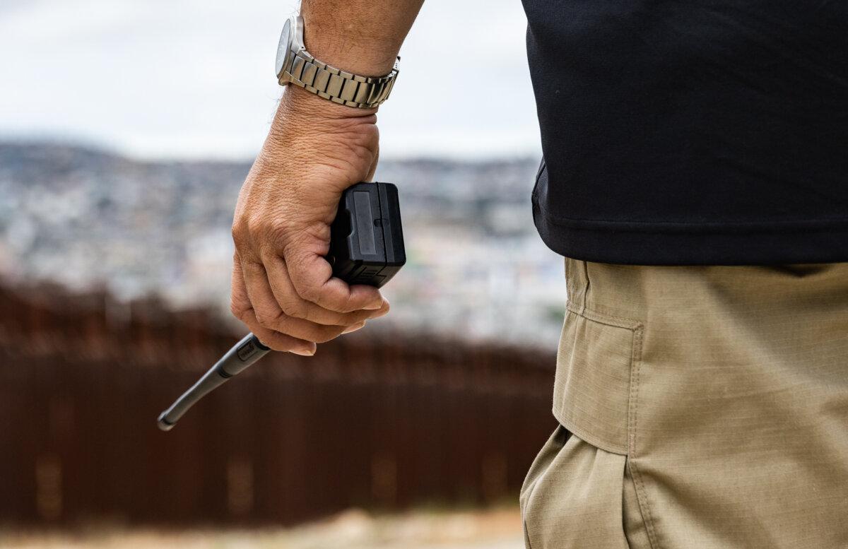 A border patrol agent listens to radio chatter near the border wall of San Diego on May 31, 2023. (John Fredricks/The Epoch Times)