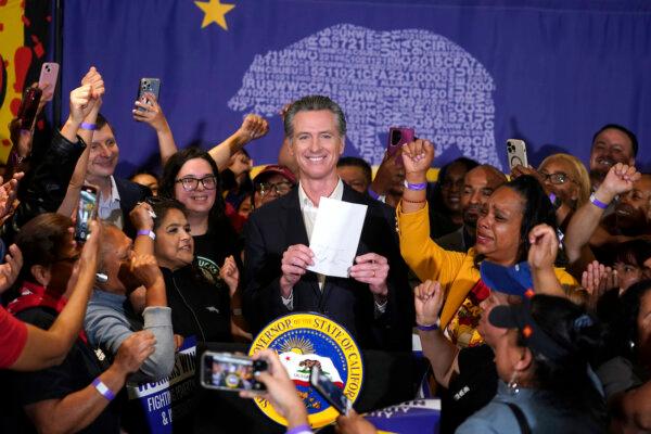 California Gov. Gavin Newsom signs the fast food bill surrounded by fast food workers at the SEIU Local 721 in Los Angeles, on Sept. 28, 2023. (AP Photo/Damian Dovarganes)