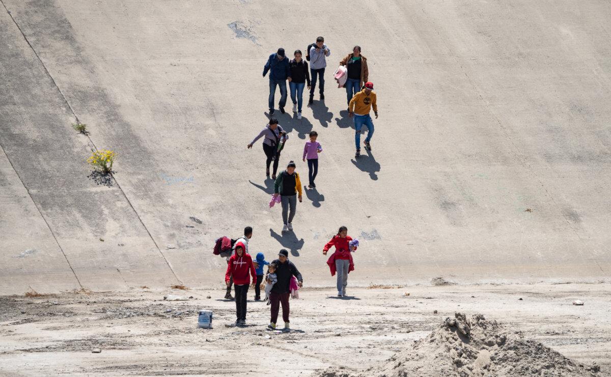 Migrants prepare to cross the Tijuana River from Mexico toward the United States on May 11, 2023. (John Fredricks/The Epoch Times)