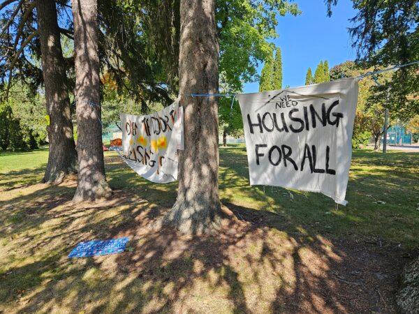 A sign hangs near an encampment on King Street in Cobourg, Ont., on Oct. 2, 2023. (Tara MacIsaac/The Epoch Times)