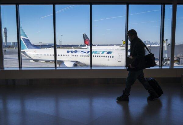 Passengers walk past Air Canada and WestJet planes at Calgary International Airport in Calgary, Alta., on Aug. 31, 2022. (The Canadian Press/Jeff McIntosh)