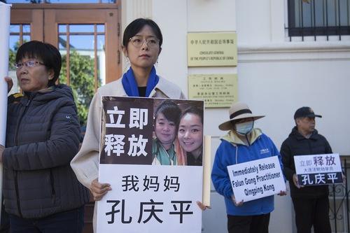 Liu Zhitong holds a photo of her mother during an event at the Chinese Consulate in San Francisco on June 19, 2023. The board reads, “Immediately release my mother Kong Qingping.” (Courtesy of Minghui.org)