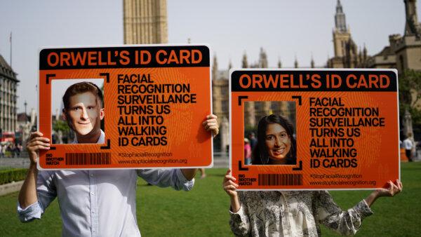 An undated image showing two activists holding up placards and wearing masks of policing minister Chris Philp (L) and Home Secretary Suella Braverman (R) outside the Houses of Parliament in Westminster, London. (Big Brother Watch)