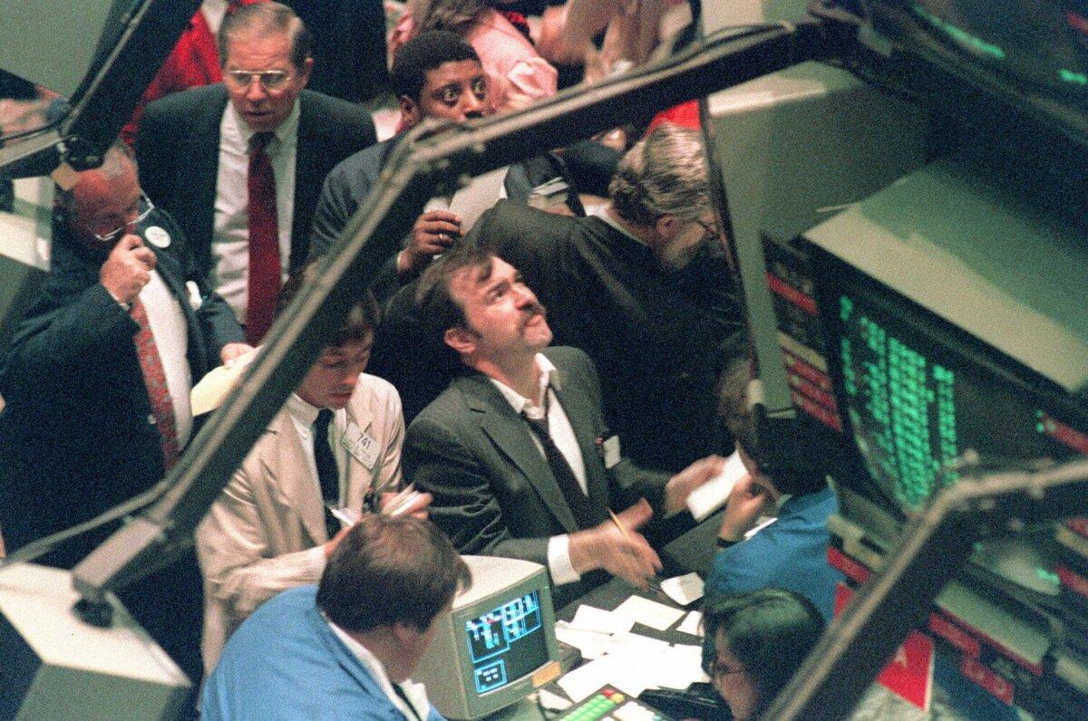 A trader (c) on the New York Stock Exchange looks at stock rates 19 October 1987 as stocks were devastated during one of the most frantic days in the exchange's history. The Dow Jones index plummeted over 200 points in record trading. (Maria R. Bastone/AFP via Getty Images)