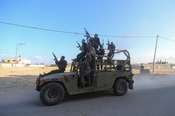 Palestinian terrorists ride an Israeli military vehicle that was seized by terrorists who infiltrated areas of southern Israel, in the northern Gaza Strip, on Oct. 7, 2023. (Ahmed Zakot/Reuters)