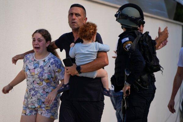 Israeli police officers evacuate a family from a site hit by a rocket fired from the Gaza Strip, in Ashkelon, southern Israel, on Oct. 7, 2023. (Tsafrir Abayov/AP Photo)