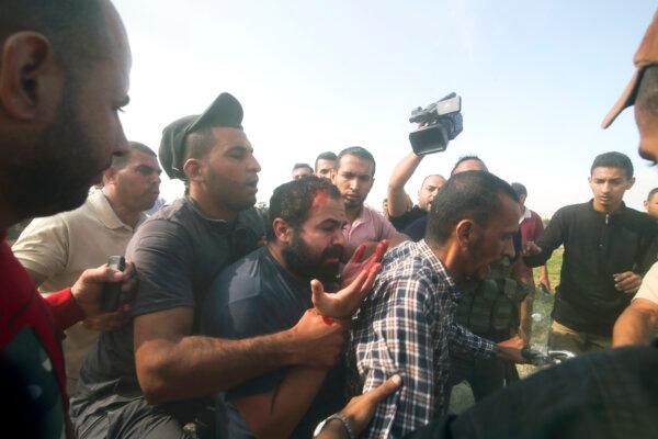 Palestinians transport a captured Israeli civilian, center, from Kibbutz Kfar Azza into the Gaza Strip on Oct. 7, 2023. (AP Photo/Hatem Ali)