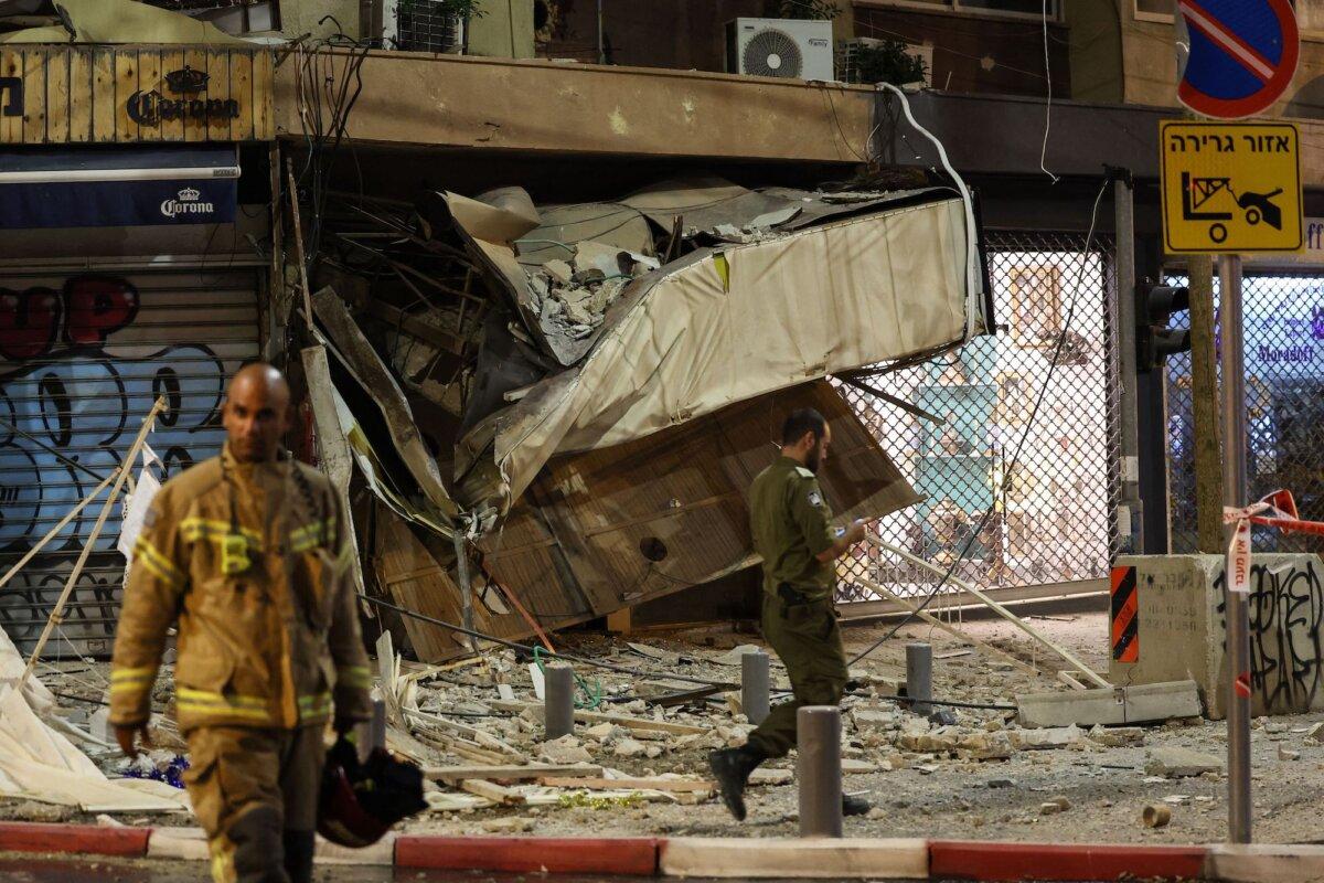 A rescuer walks in front of a damaged shop in Tel Aviv, after it was hit by a rocket fired by Hamas terrorists from the Gaza Strip on Oct. 7, 2023. (Jack Guez/AFP/Getty Images)