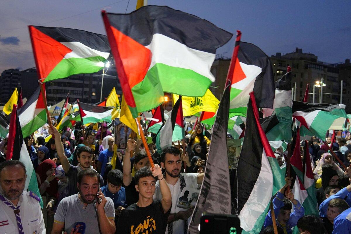 People wave Hezbollah and Palestinian flags during a rally in celebration of the attacks carried out by the Hamas terrorist group against Israel, in the southern Beirut suburb of Dahiyeh, Lebanon, on Oct. 7, 2023. (AP Photo/Bilal Hussein)