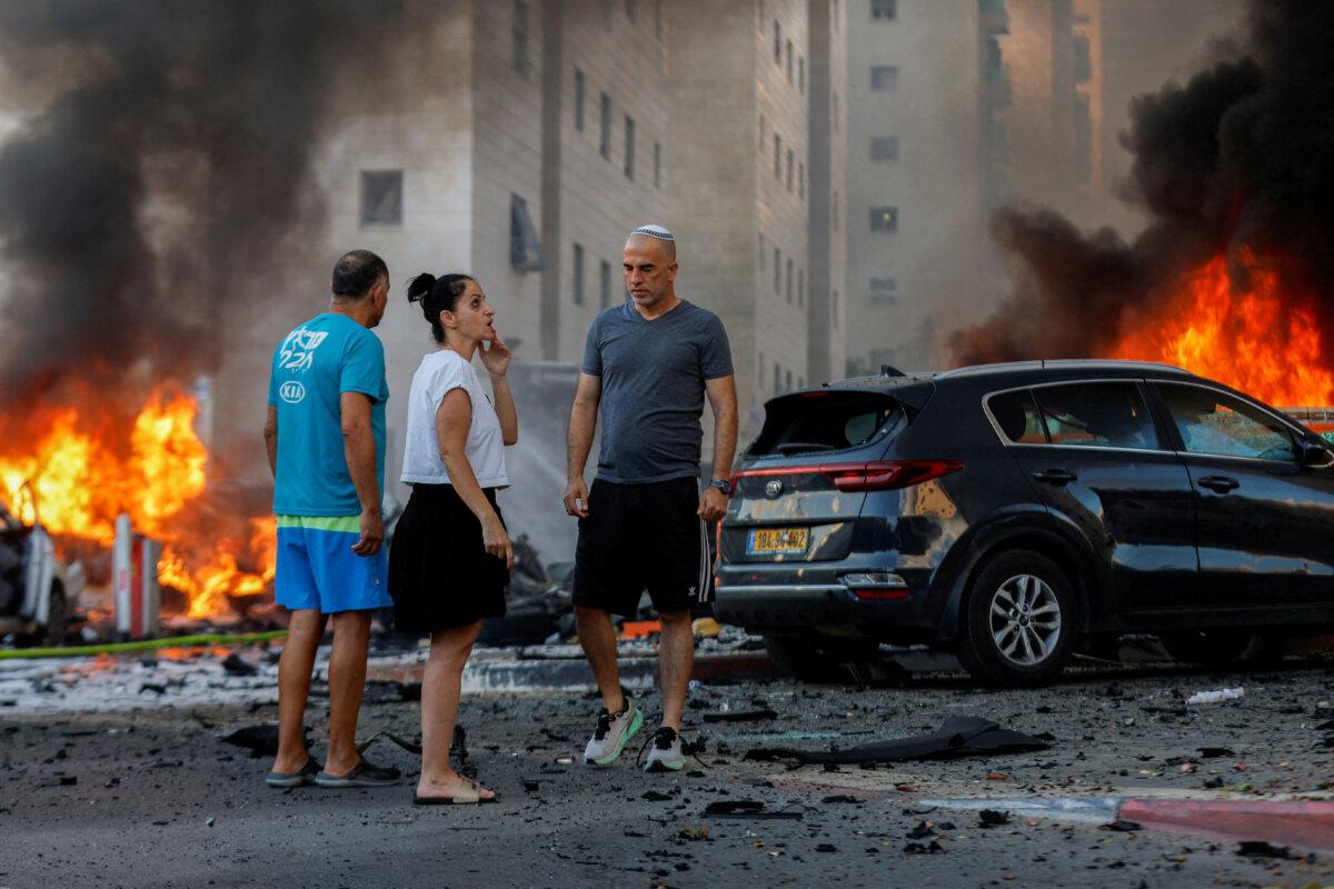 People react near a fire after rockets were launched from the Gaza Strip, in Ashkelon, Israel, on Oct. 7, 2023. (Reuters/Amir Cohen)