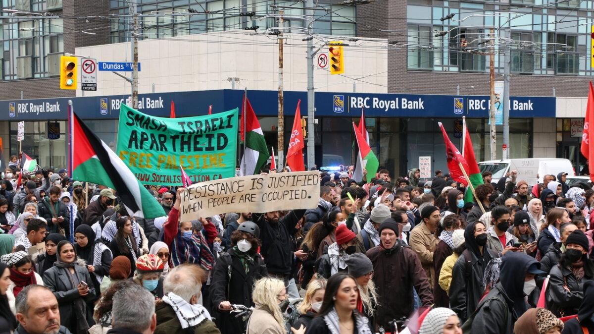 Pro-Palestine protesters were seen holding large banners, including one that reads “Smash Israeli Apartheid, Free Palestine," and another that reads "Resistance is Justified When People Are Occupied,” as they marched along Bay Street in downtown Toronto on Oct. 9, 2023. (Andrew Chen/The Epoch Times)