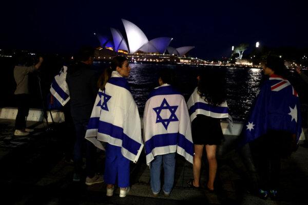 People with Israeli flags watch the Opera House while it is illuminated in blue to show solidarity with Israel in Sydney, Australia, on Oct. 9, 2023. (David Gray/AFP via Getty Images)