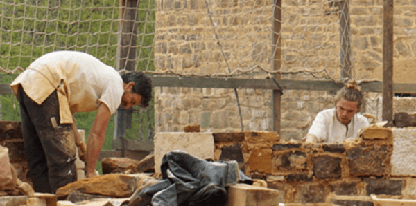  Stone masons setting stones with limestone mortar 2023. (Courtesy of Guédelon)