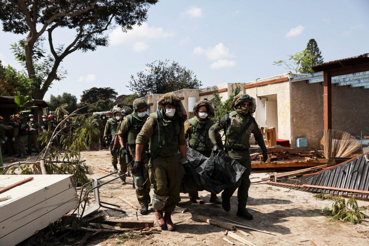 Israeli soldiers carry the body of a victim of a terrorist attack from Gaza at the Kfar Aza kibbutz, in Israel, on Oct. 10, 2023. (Violeta Santos Moura/Reuters)