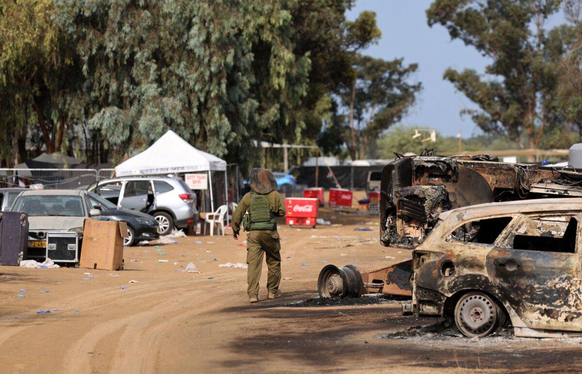 An Israeli soldier walks past burnt-out vehicles near the Re’im kibbutz in southern Israel after the attack on the Supernova music festival by Hamas terrorists, on Oct. 10, 2023. (Jack Guez/AFP via Getty Images)