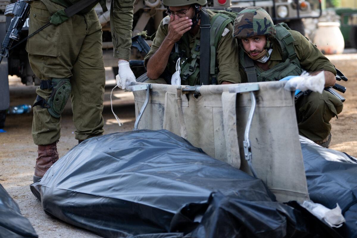 An IDF soldier reacts and covers his face before removing the body of a civilian killed days earlier in an attack by Hamas militants in Kfar Aza, Israel, on October 10, 2023. (Alexi J. Rosenfeld/Getty Images)