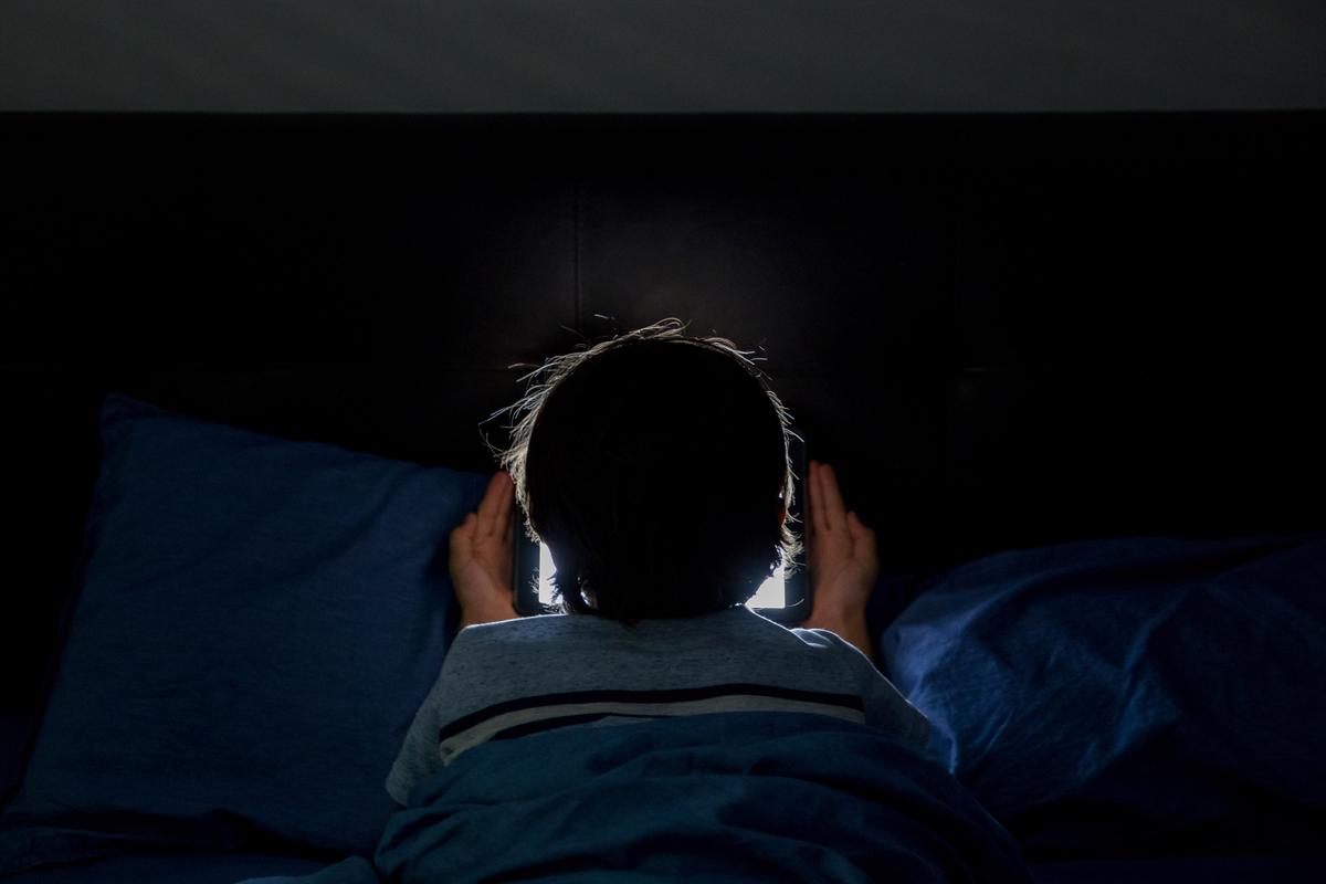 A child playing on a tablet in bed. (Illustration - MPIX/Shutterstock)
