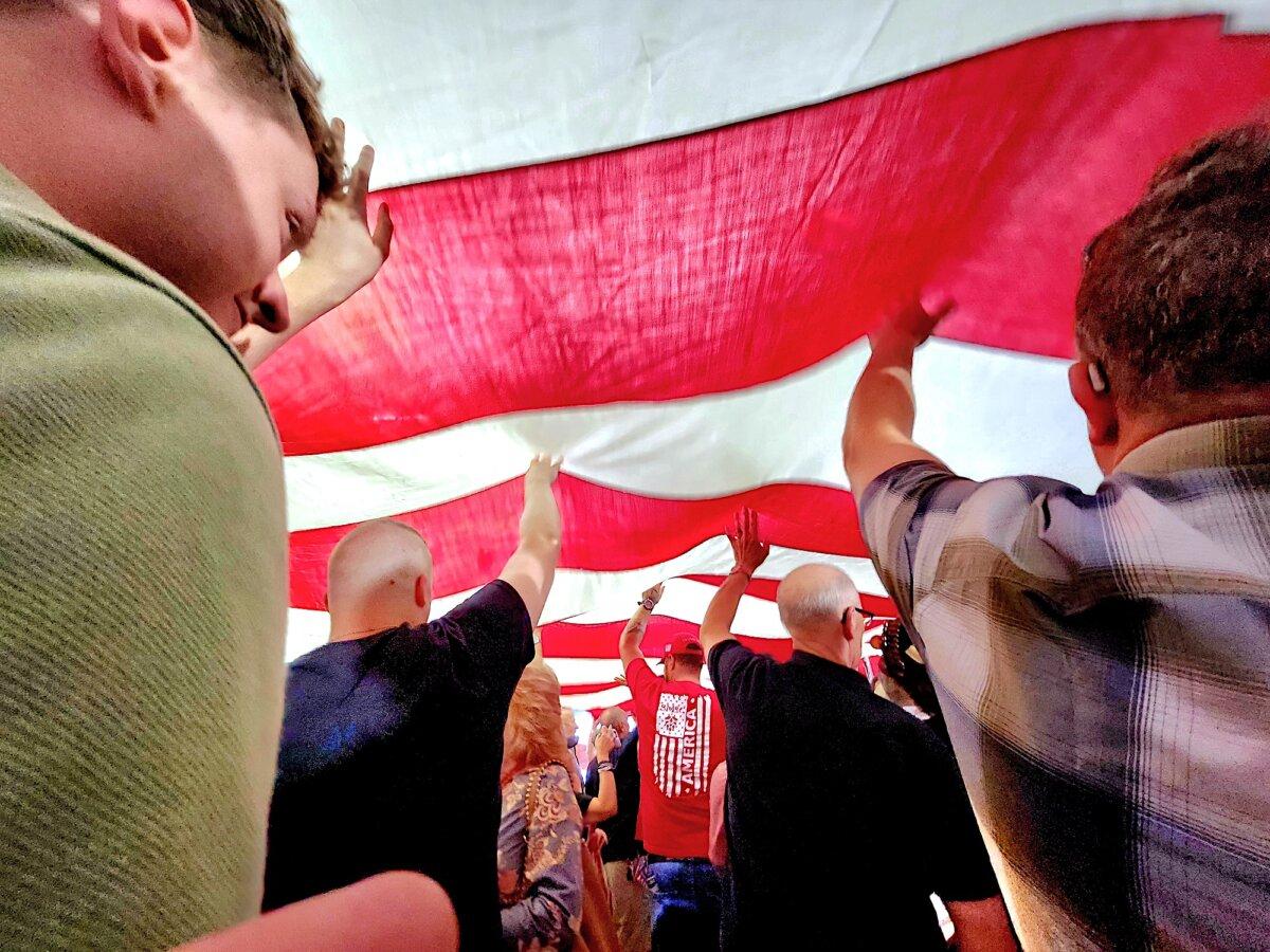 Supporters of Arizona Republican candidate for U.S. Senate, Kari Lake, unfold a 50-foot flag once flown aboard the USS Enterprise at the Kari Lake U.S. Senate campaign launch event in Scottsdale, Ariz., on Oct. 10, 2023. (Allan Stein/The Epoch Times)