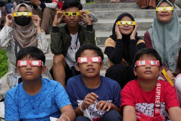 Youths wear protective glasses to watch a hybrid solar eclipse in Jakarta, Indonesia, on April 20, 2023. (Tatan Syuflana/AP Photo)