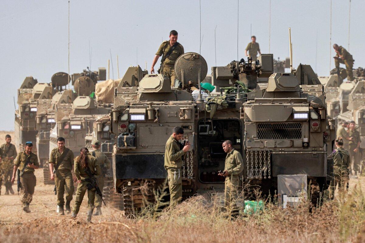 Israeli army soldiers stand near stationed Namer armored personnel carriers (APCs) at a position near the border with Gaza in southern Israel on Oct. 11, 2023. (Menahem Kahana/AFP via Getty Images)