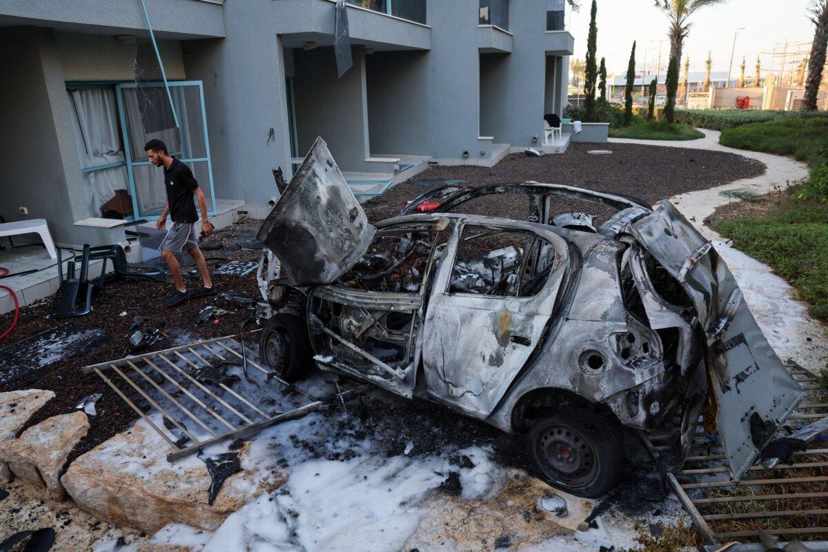 A man walks next to a car destroyed in a rocket attack from the Gaza Strip in the southern Israeli city of Ashkelon on Oct. 10, 2023. (Jack Guez/AFP via Getty Images)