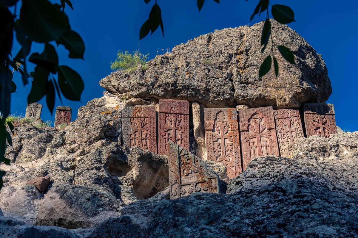 Khachkars depicting crucifix motifs are mounted along the cliffside at Geghard Monastery in Armenia. (Xavier Llauger Dalmau/Shutterstock)