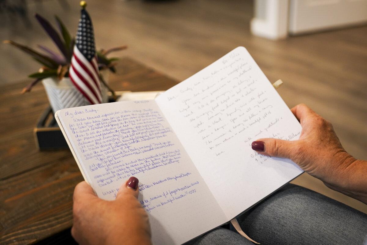  Ms. McGrew holds a notebook in which veterans write their thoughts after leaving the retreat. (Madalina Vasiliu/The Epoch Times)