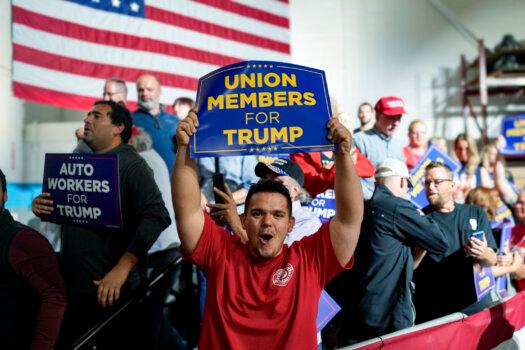 A union member, Isaiah Goddard, waves a banner while waiting for former President Donald Trump to speak at a campaign rally event in Clinton Township, Mich., on Sept. 27, 2023. (Courtesy of Isaiah Goddard)