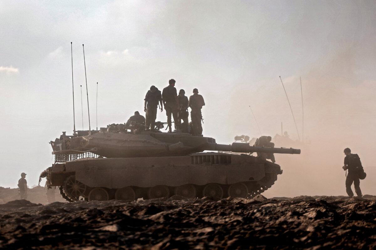 Israeli troops stand atop a tank in a field near the Be'eri kibbutz in southern Israel on Oct. 14, 2023. (Thomas Coex/AFP via Getty Images)