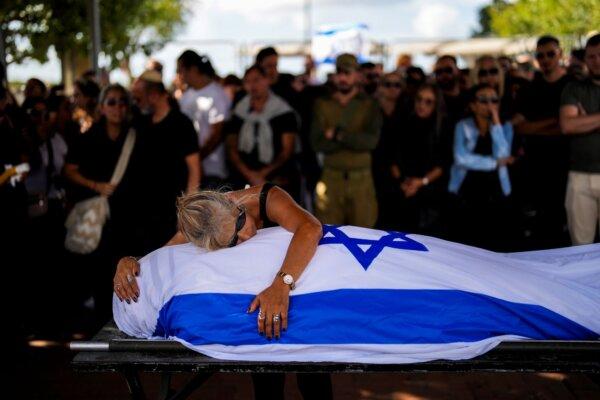 Antonio Macías' mother cries over her son's body covered with the Israeli flag at Pardes Haim cemetery in Kfar Saba, near Tel Aviv, Israel, on Oct. 15, 2023. (Francisco Seco/AP)