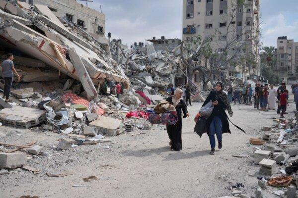Palestinian women walk by buildings destroyed in Israeli airstrikes in Nuseirat camp in the central Gaza Strip, on Oct. 16, 2023. (Hatem Moussa/AP)
