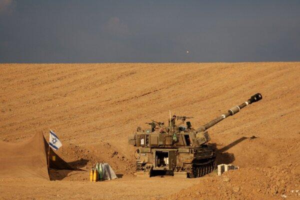 An Israeli soldier shades his eyes from the sun as he stands on a self-propelled howitzer near Israel's border with the Gaza Strip, in southern Israel, on Oct. 17, 2023. (Violeta Santos Moura/Reuters)