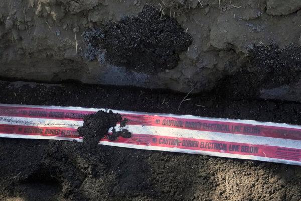 Tape warning that electrical lines are buried below is rolled out as a Pacific Gas and Electric crew works on burying power lines in Vacaville, Calif., on Oct. 11, 2023. (Jeff Chiu/AP Photo)