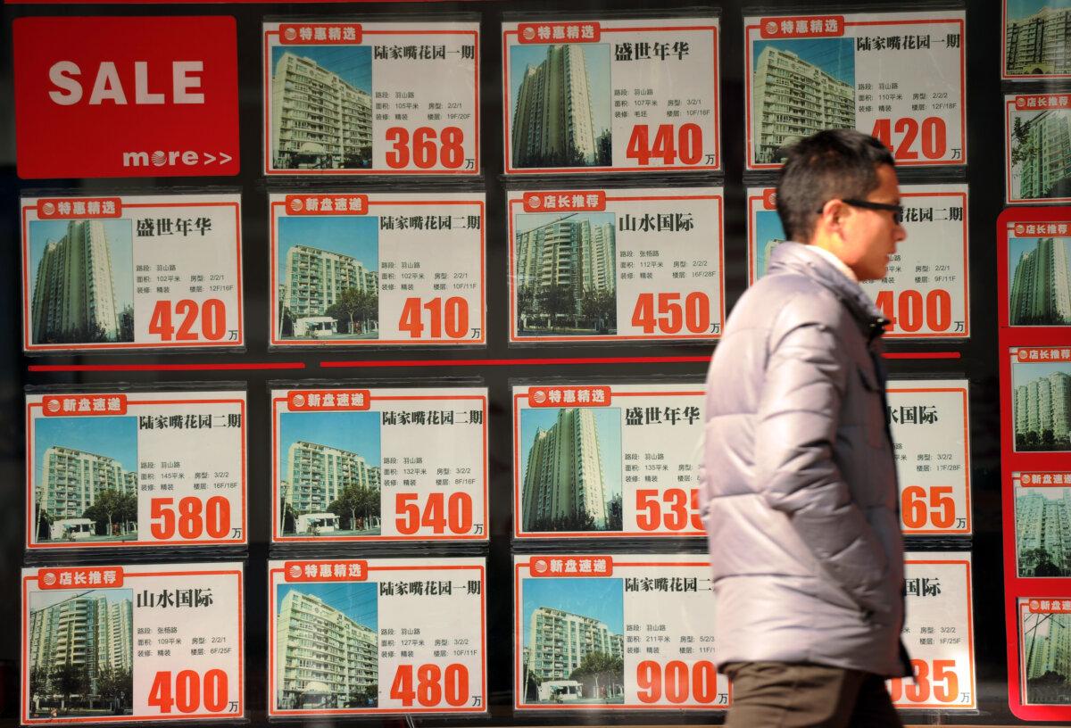 A man was walking in front of a real estate agent's window in Shanghai on Dec. 4, 2012. (Peter Parks/AFP via Getty Images)