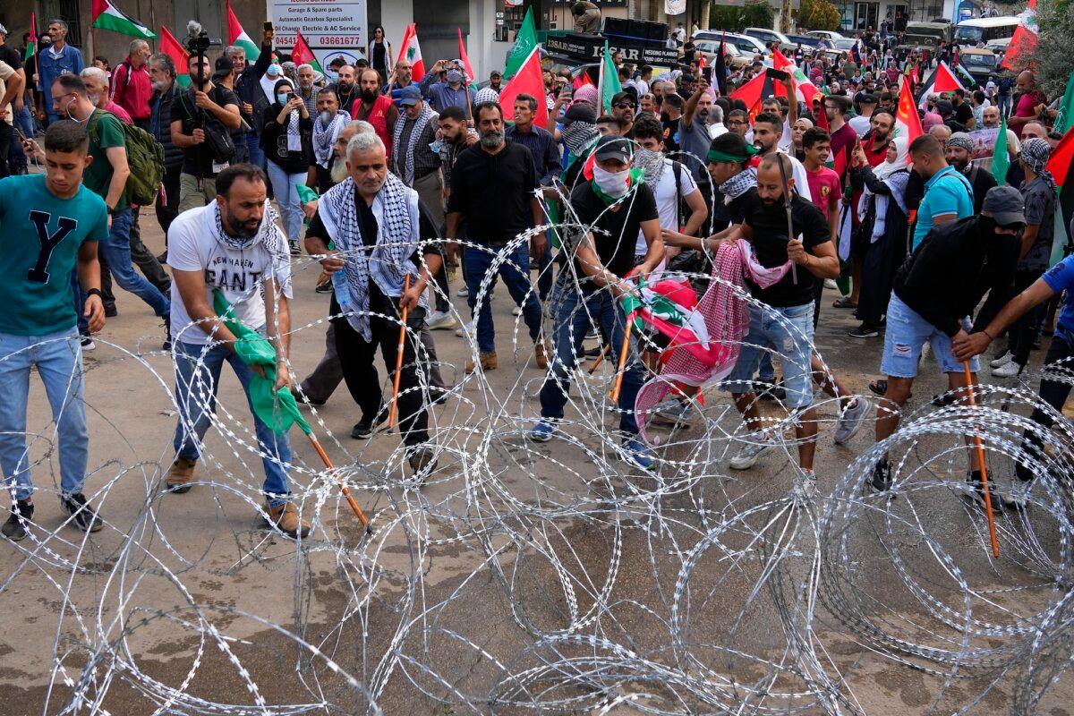 Protesters try to remove barbed wires that block a road leading to the U.S. embassy, during a demonstration in Beirut, Lebanon, on Oct. 18, 2023. (Bilal Hussein/AP Photo)