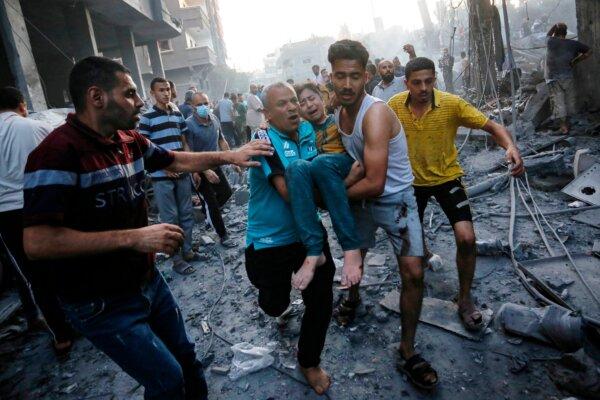 Graphic content/Men carry away a wounded child following an Israeli strike on the town of Deir Al-Balah in the central Gaza Strip on Oct. 18, 2023. (Mohammed Faiq/AFP via Getty Images)