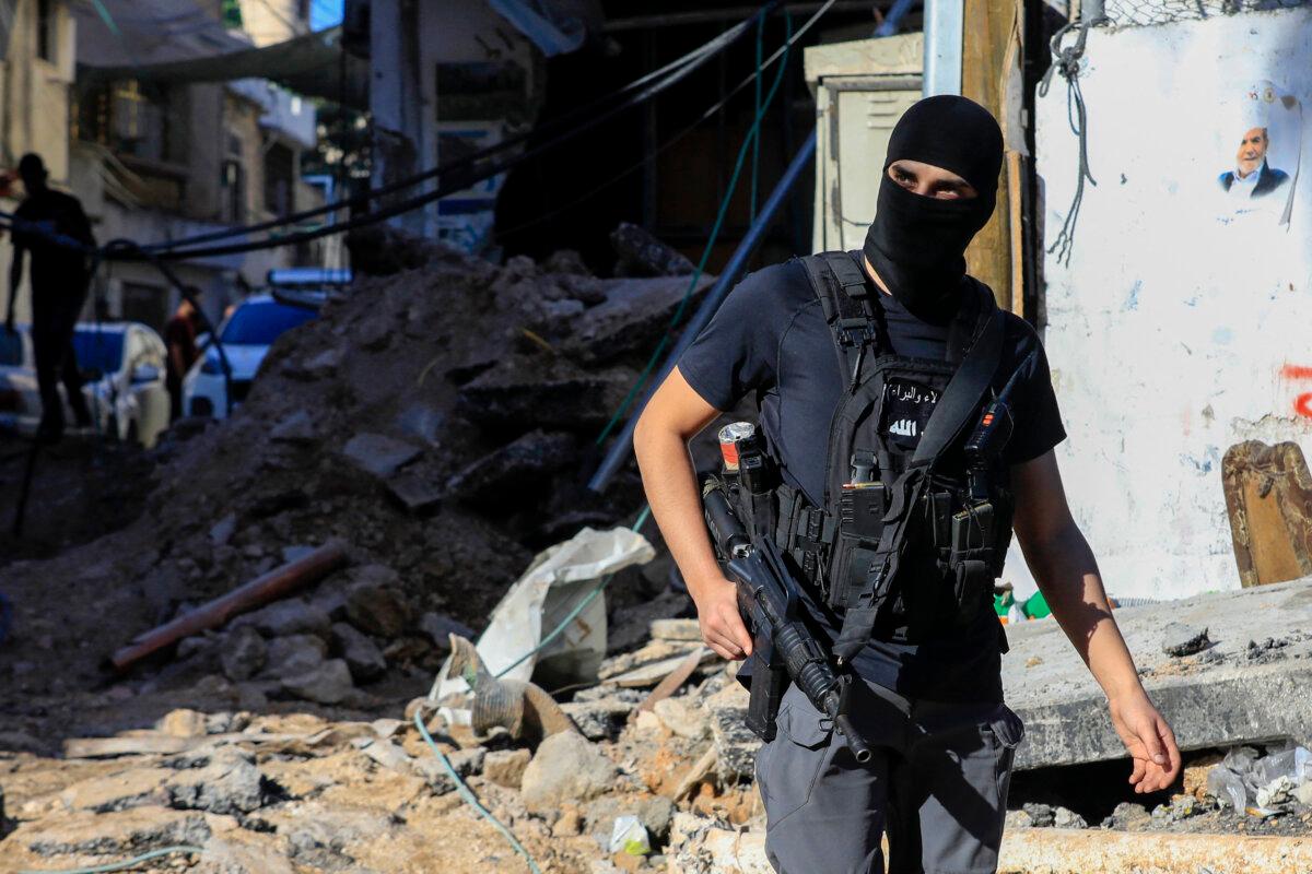 An armed Palestinian man walks amid the rubble of a building damaged during a raid by Israeli troops at the Nur Shams refugee camp near the northern city of Tulkarm in the West Bank on Oct. 20, 2023. (Zain Jaafar/AFP via Getty Images)