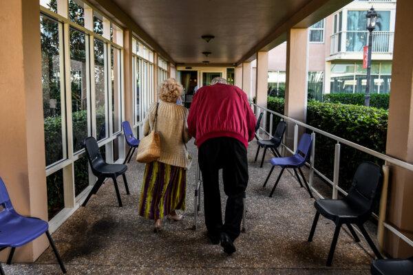 An elderly resident is escorted toward the John Knox Village, a retirement community in Pompano Beach, Fla., on March 21, 2020. (Chandan Khanna/AFP via Getty Images)