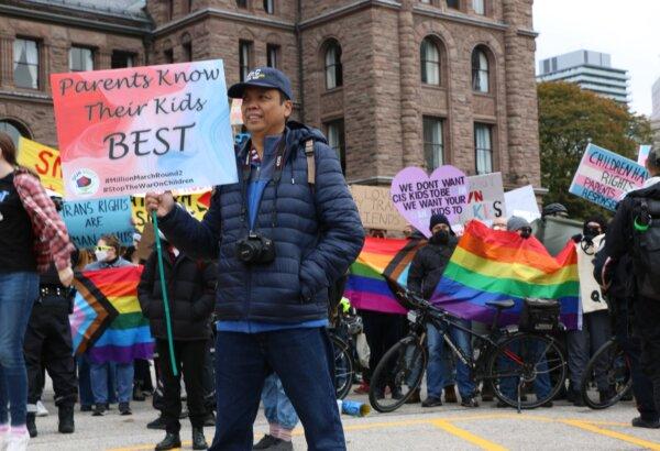 A pro-parental rights protester is seen with counter-protesters in the background at Queen's Park in Toronto on Oct. 21, 2023. (Andrew Chen/The Epoch Times)