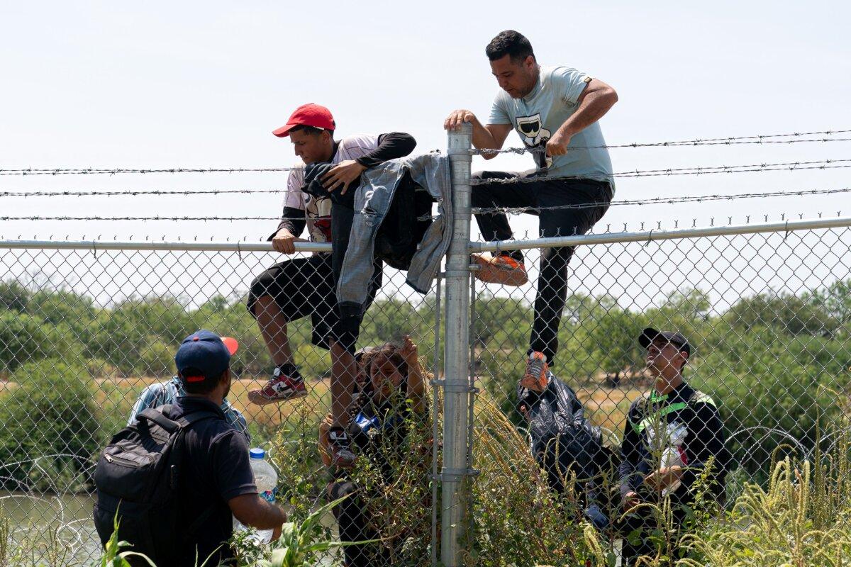  Illegal immigrants jump over the barbed wire fence into the United States from Mexico, in Eagle Pass, Texas, on Aug. 25, 2023. (Suzanne Cordeiro/AFP via Getty Images)