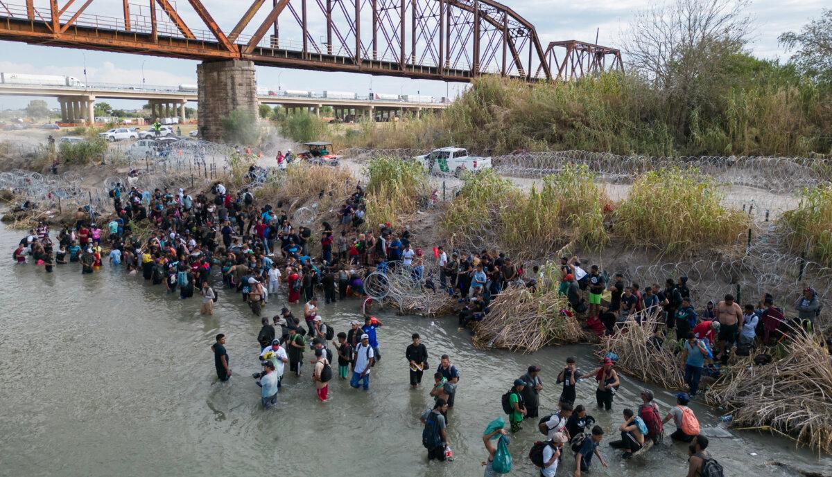 Elon Musk Says Biden Administration ‘Actively Aiding Illegal Immigration’ | USNN World News Migrants wait in the Rio Grande for an opening in the razor wire barrier, to cross into the United States, in Eagle Pass, Texas, on Sept. 25, 2023. (Andrew Caballero-Reynolds/AFP via Getty Images)