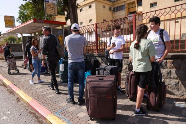 People with their luggage wait at a bus stop in the northern Israeli town of Kiryat Shmona on the border with Lebanon, to be evacuated to a safer location on Oct. 22, 2023. (JALAA MAREY/AFP via Getty Images)