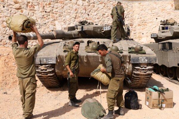 Israeli soldiers make preparations in front of Merkava tanks as they man a position at an undisclosed location on the border with Lebanon on Oct. 22, 2023. (Jalaa Marey/AFP via Getty Images)