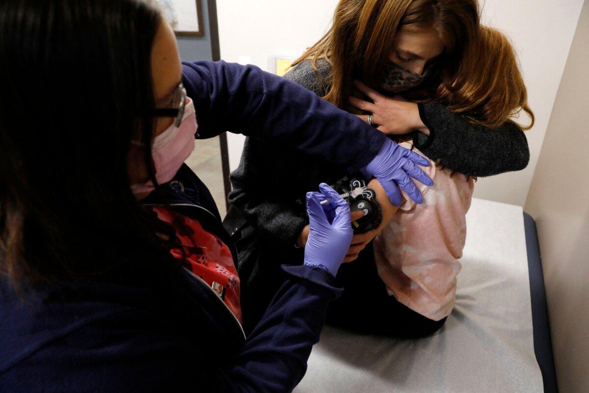 A 6-year-old child is comforted by her mother as she receives her first dose of the Pfizer-BioNTech Covid-19 vaccine by medical assistant Alli Shapiro at the Child Health Associates office in Novi, Mich., on Nov. 3, 2021. (Jeff Kowalsky/AFP via Getty Images)