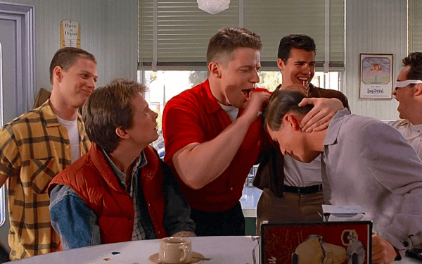(L–R, foreground) Marty McFly (Michael J. Fox), Biff Tannen (Tom Wilson), and George McFly (Crispin Glover) in "Back to the Future." (Universal Pictures)