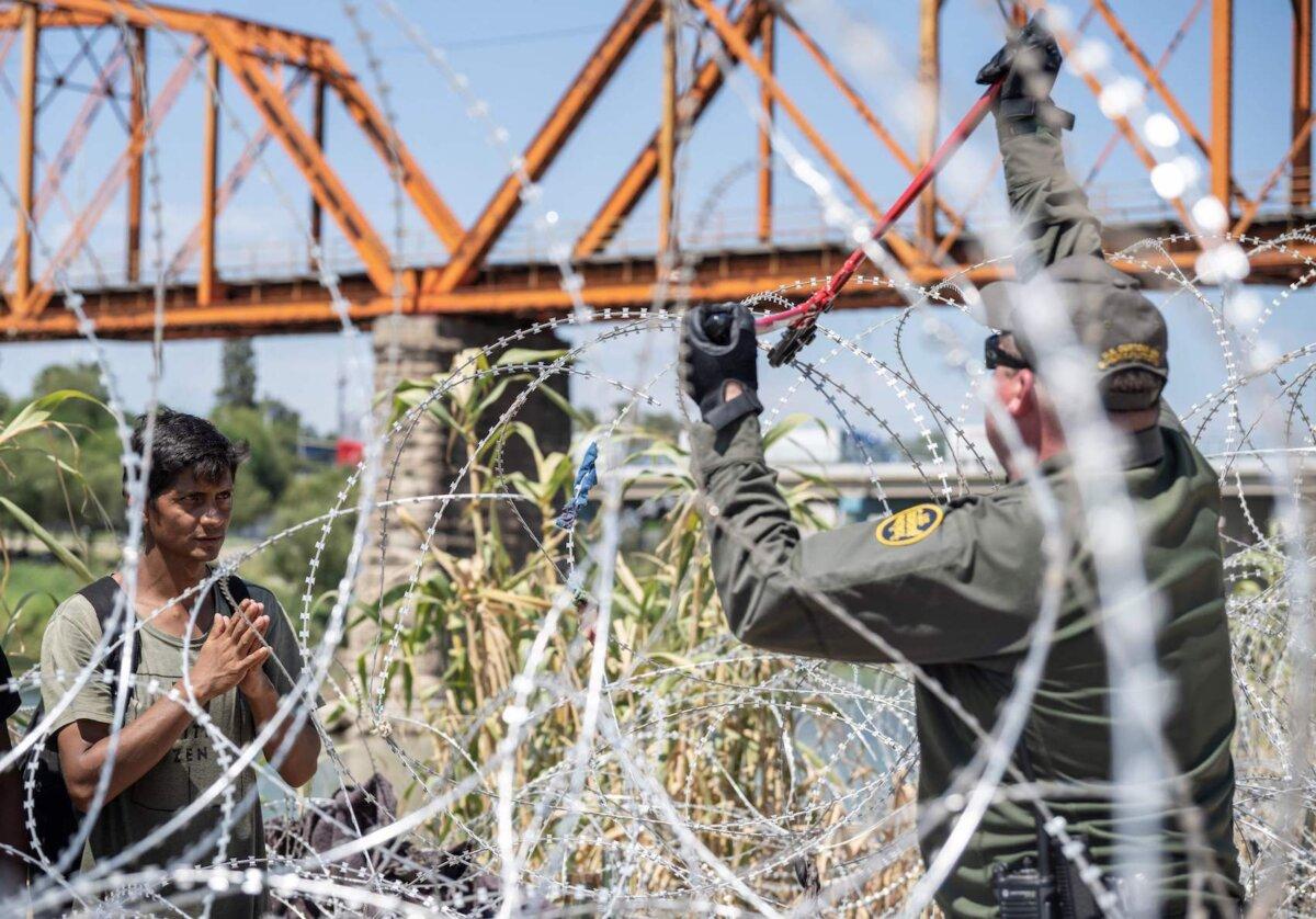 A migrant from Venezuela prays as he waits for a U.S. Border Patrol agent to cut razor wire after he crossed the Rio Grande to Eagle Pass, Texas, on Sept. 24, 2023. (Andrew Caballero-Reynolds/AFP via Getty Images)