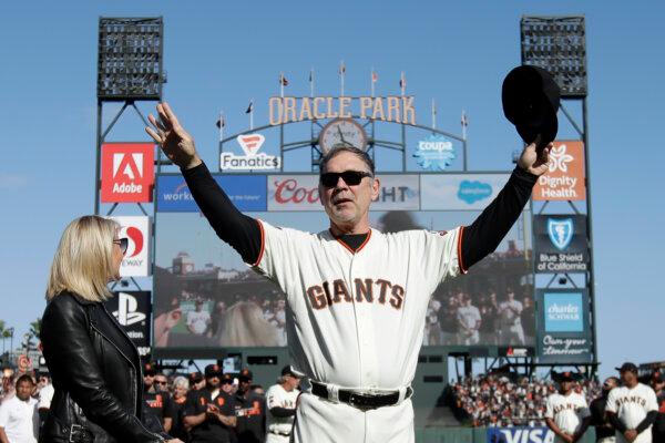 Then Manager Bruce Bochy of the San Francisco Giants, center, gestures toward fans next to his wife Kim during a ceremony honoring Bochy after a game between the San Francisco Giants and the Los Angeles Dodgers in San Fransisco on Sept. 29, 2019. (Jeff Chiu - Pool/Getty Images)