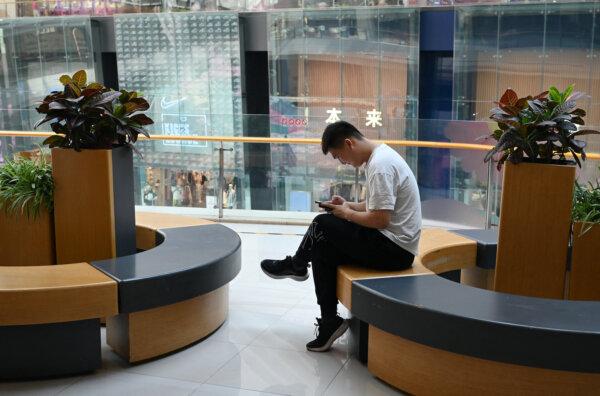 A man checks his phone while resting in a shopping mall in Beijing on July 18, 2023. (Greg Baker/AFP via Getty Images)