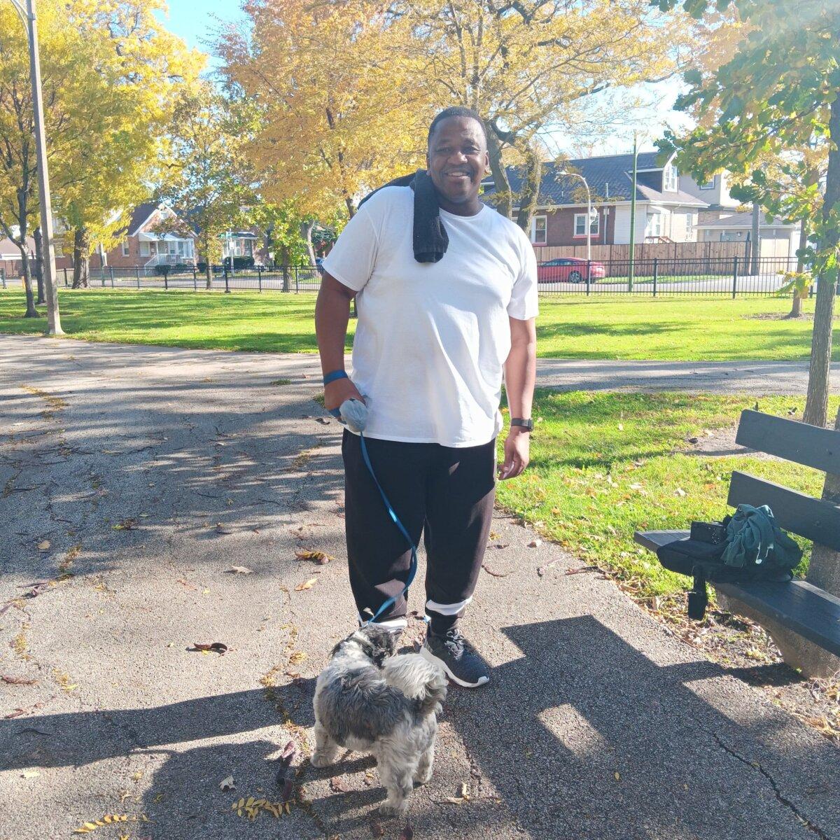 Kieron Scott, one of many residents who object to plans that could see hundreds of illegal immigrants claiming Amundsen's fieldhouse and displacing local programming, walks his dog, Duke, through Chicago's Amundsen Park, on Oct. 24, 2023. (Nathan Worcester/The Epoch Times)