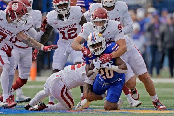 Kansas running back Daniel Hishaw Jr. (20) is tackled by Oklahoma defensive lineman Rondell Bothroyd (80) as he runs for a first down during the first half of an NCAA college football game in Lawrence, Kan., on Oct. 28, 2023 (Charlie Riedel/AP Photo)